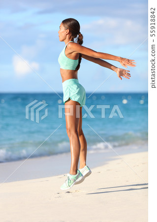 Fit woman training legs with hiit workout jumping squats exercises on beach Fit woman training legs with hiit workout jumping squats exercises on beach 55918842
