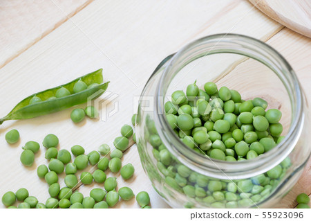 Fresh green peas in a glass jar on bright wooden background with copy space. Top view. 55923096