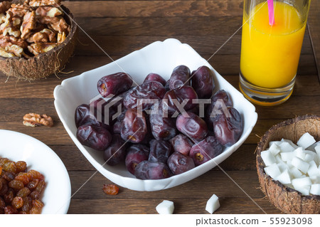 Delicious dietary breakfast. White dish with date fruits inside, glass of freshly squeezed orange Delicious dietary breakfast. White dish with date fruits inside, glass of freshly squeezed orange 55923098