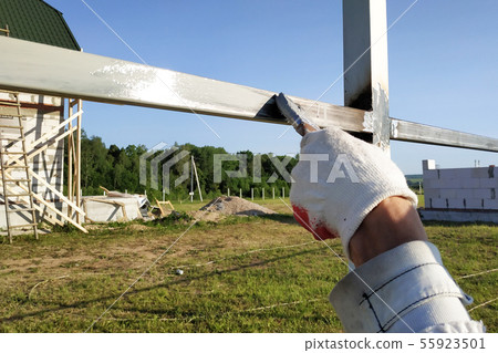 The worker paints the profile of a metal fence The worker paints the profile of a metal fence 55923501