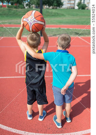 Two basketball players are standing on the red pla 55924014