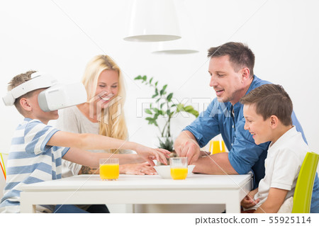 Happy family at home on living room sofa having fun playing games using virtual reality headset 55925114