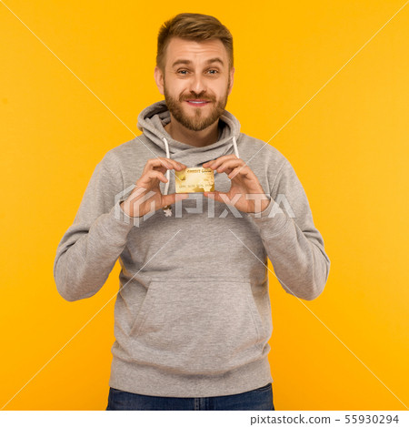 Attractive man in a gray hoodie holds a credit 55930294