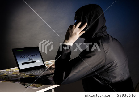 Anonymous hacker in mask sitting sideways uses a 55930516