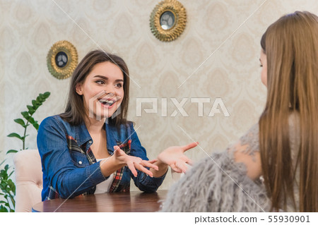 Pretty young women sitting in a cafe. A beautiful and warm shot of a Caucasian girl in casual Pretty young women sitting in a cafe. A beautiful and warm shot of a Caucasian girl in casual 55930901