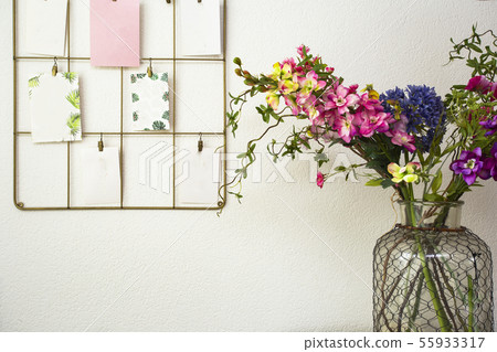 Bouquet of colorful flowers white wall and post cards hanging, modern interior 55933317