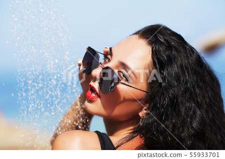 Tenned beautiful woman in black bikini and sunlasses sitting in swimming pool with cocktail Tenned beautiful woman in black bikini and sunlasses sitting in swimming pool with cocktail 55933701
