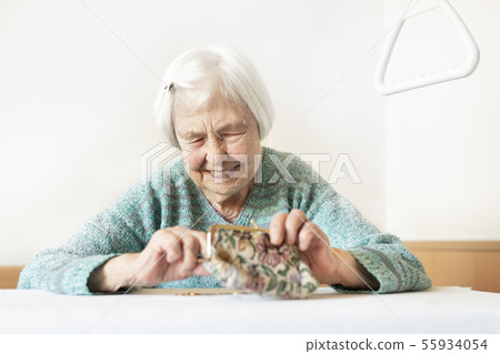 Cheerful elderly 96 years old woman sitting at table at home happy with her pension savings in her 55934054
