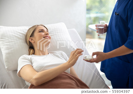 Doctor giving medicine to young woman in hospital room 55934397
