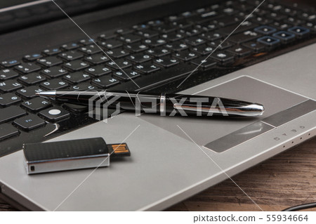 Pen and usb flash on laptop keyboard. Desktop Pen and usb flash on laptop keyboard. Desktop 55934664