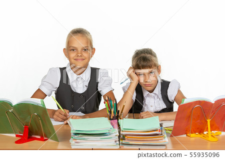 Two schoolgirls at a desk, one funny, the other 55935096
