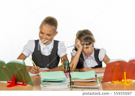 Two schoolgirls at a desk, one excellent student, 55935097