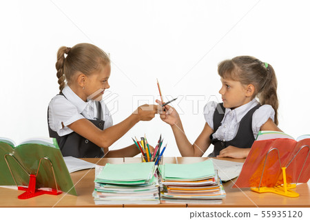 Two girls fight with pencils at a school desk Two girls fight with pencils at a school desk 55935120