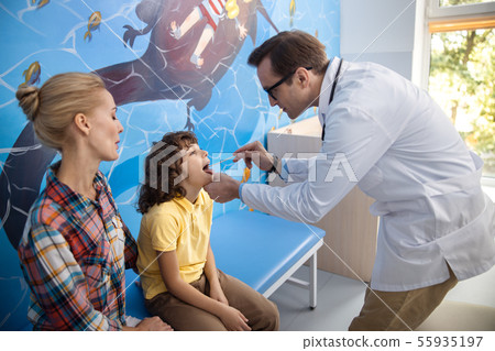 Boy is having examined sore throat at doctor stock photo 55935197