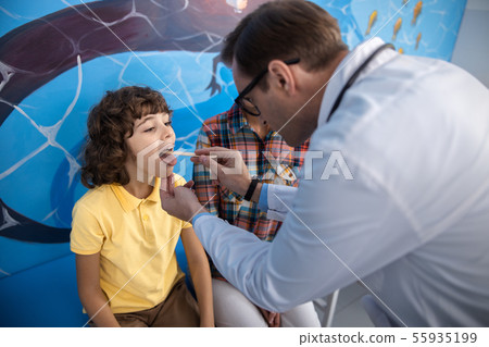 Male pediatrician is examining boy throat stock photo 55935199