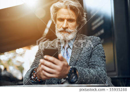 Mature man concentrated on smartphone stock photo Mature man concentrated on smartphone stock photo 55935288