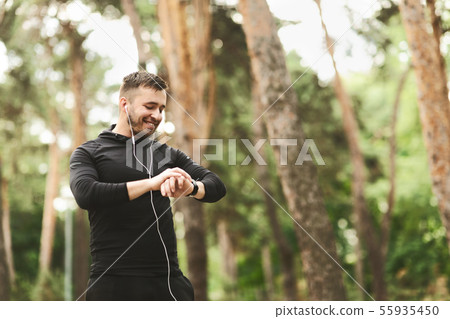 Male runner using smart watch to monitor his performance. 55935450
