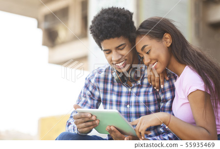 Young couple browsing social media on digital tablet outdoors 55935469