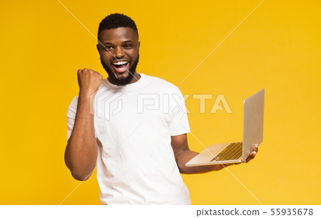 Excited african man celebrating win with laptop Excited african man celebrating win with laptop 55935678