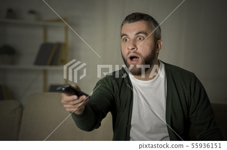 Caucasian man watching tv at home at night Caucasian man watching tv at home at night 55936151