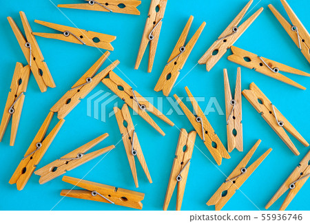 Wooden yellow clothespins are scattered on a cyan-blue background. Frame of clothespins. View from 55936746