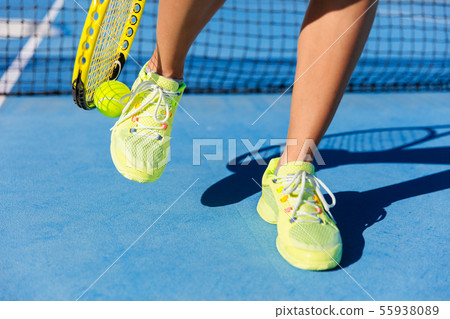 Sports athlete picking up ball with tennis racket Sports athlete picking up ball with tennis racket 55938089