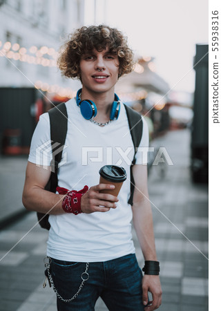 Relaxed student with coffee in the street smiling 55938316