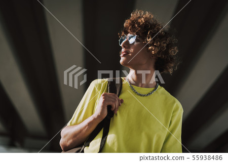 Smiling curly young man carrying black backpack Smiling curly young man carrying black backpack 55938486