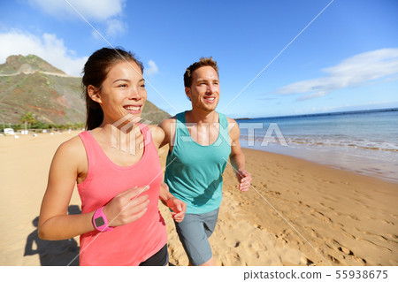 Running couple jogging on beach exercising Running couple jogging on beach exercising 55938675