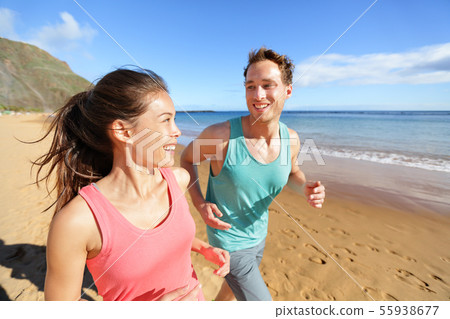 Young couple talking running on beach jogging Young couple talking running on beach jogging 55938677