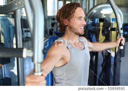 Gym center man working out on fitness machine Gym center man working out on fitness machine 55939591