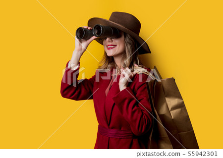 Woman in 1940s style clothes with binoculars and bags 55942301