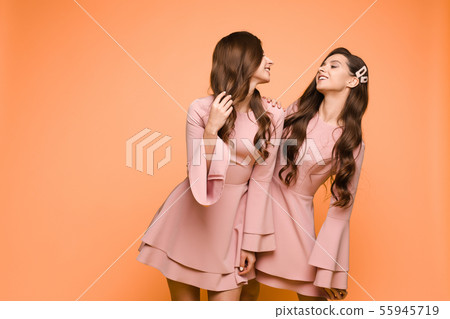 Happy sisters in pink dresses smiling and standing Happy sisters in pink dresses smiling and standing 55945719