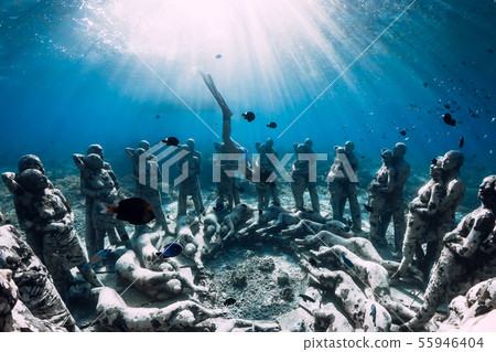 Woman freediver with fins dive near statues Woman freediver with fins dive near statues 55946404
