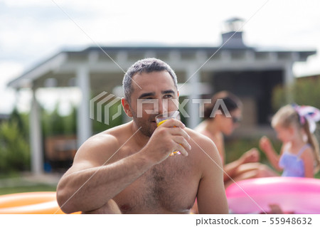 Man chilling near pool with his family at the weekend 55948632