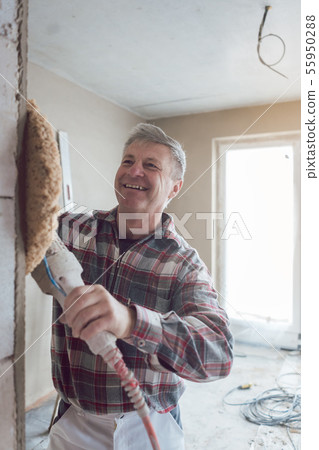 Plasterer smoothing interior wall of new homes with machine Plasterer smoothing interior wall of new homes with machine 55950288