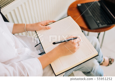 Female hands writing in a notepad, overview. 55951252