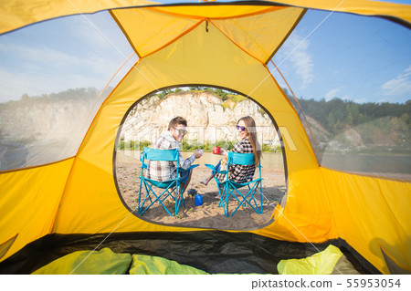 People, tourism and nature concept - Cute couple sitting with a cat near yellow tent 55953054