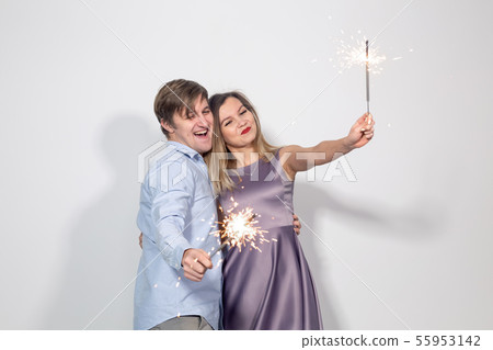Celebration, fun and holiday concept - Happy man and woman hold a firework stick or sparklers 55953142