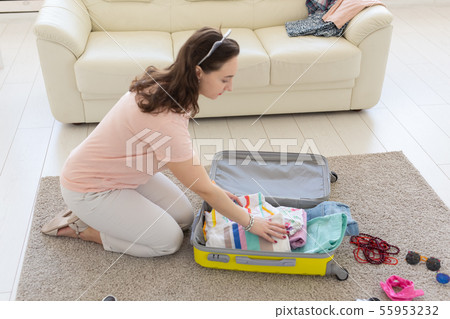 Holidays, voyage and travel concept - woman collects a yellow suitcase at home Holidays, voyage and travel concept - woman collects a yellow suitcase at home 55953232