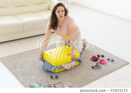 Vacation, journey and holidays concept - woman collecting clothes on the floor Vacation, journey and holidays concept - woman collecting clothes on the floor 55953235