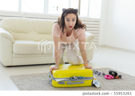 Vacation, travel and holidays concept - Woman trying to close suitcase with a lot of things Vacation, travel and holidays concept - Woman trying to close suitcase with a lot of things 55953261
