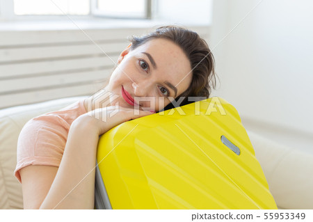 Trip, travel and holidays concept - young woman hugging her yellow suitcase 55953349
