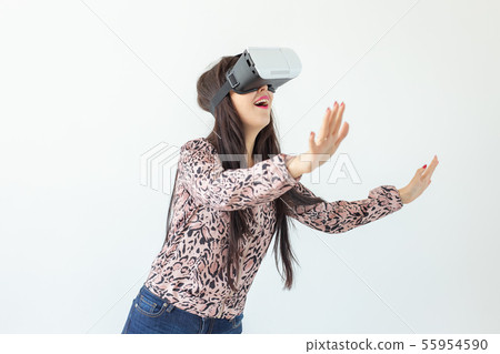 Young woman watches a movie with glasses of virtual reality standing on a white background. The 55954590