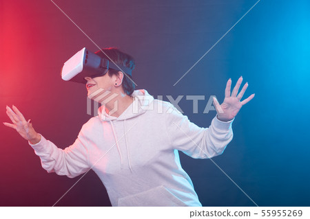 Middle-aged woman with virtual reality goggles. Studio shot, red-blue background 55955269