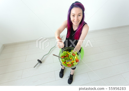 Positive mixed race hipster girl with colored hair eating a light greek salad after physical 55956283