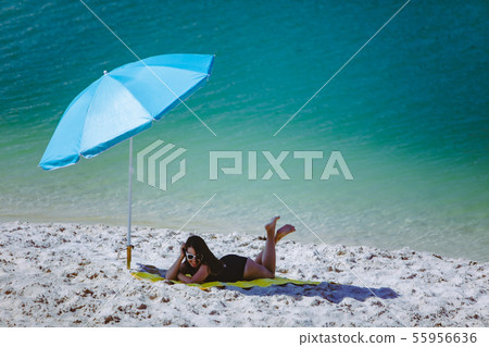 woman in swimsuit walking by sand beach blue sun umbrella and yellow blanket woman in swimsuit walking by sand beach blue sun umbrella and yellow blanket 55956636