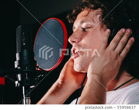 Male vocal artist with curly hair singing alone.Singer man writing song Male vocal artist with curly hair singing alone.Singer man writing song 55956637
