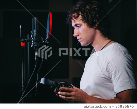Young handsome singer man puts on headphones in the studio. 55956670