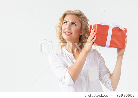 Holidays concept - Portrait of a smiling cute woman opening gift box isolated on a white background Holidays concept - Portrait of a smiling cute woman opening gift box isolated on a white background 55956693